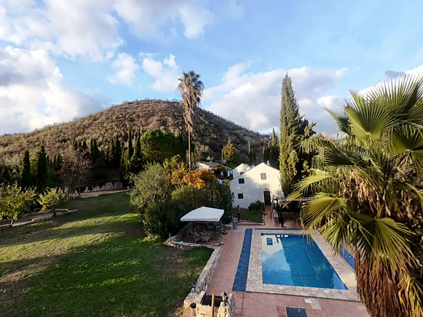 Vooraanzicht van een traditioneel Andalusisch cortijo met stenen muren en een zonnige binnenplaats